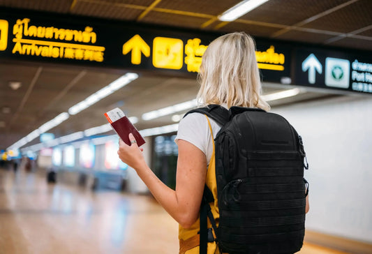 Tjej som går på flygplats med en ryggsätt och ett pass i handen
